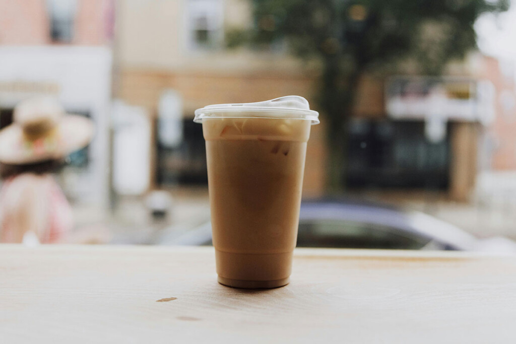 A takeaway plastic cup with coffee on a table
