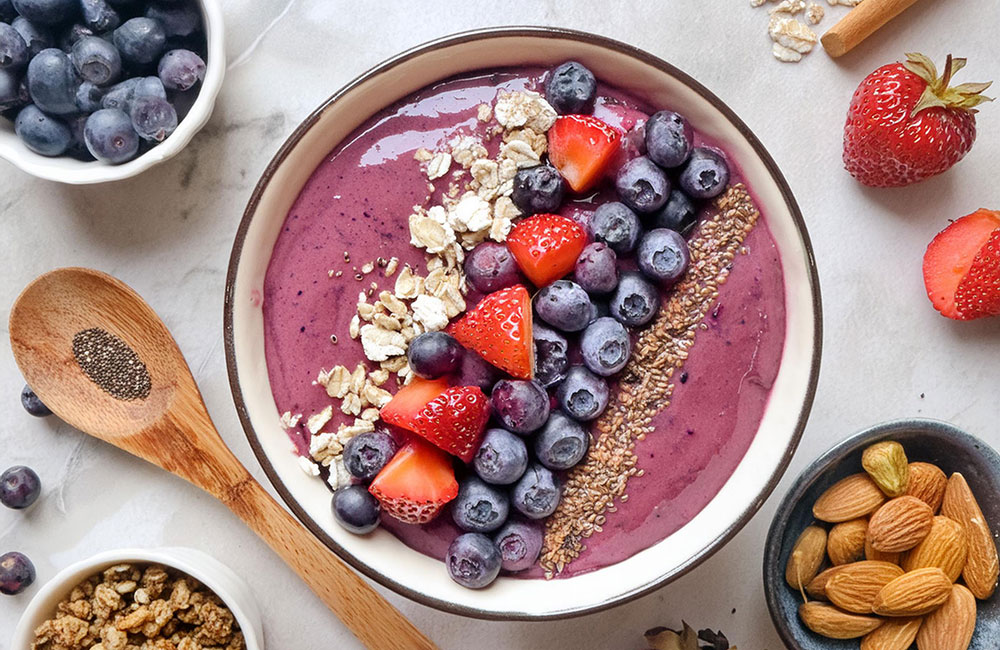 Berry smoothie bowl in a wooden bowl with a wooden spoon